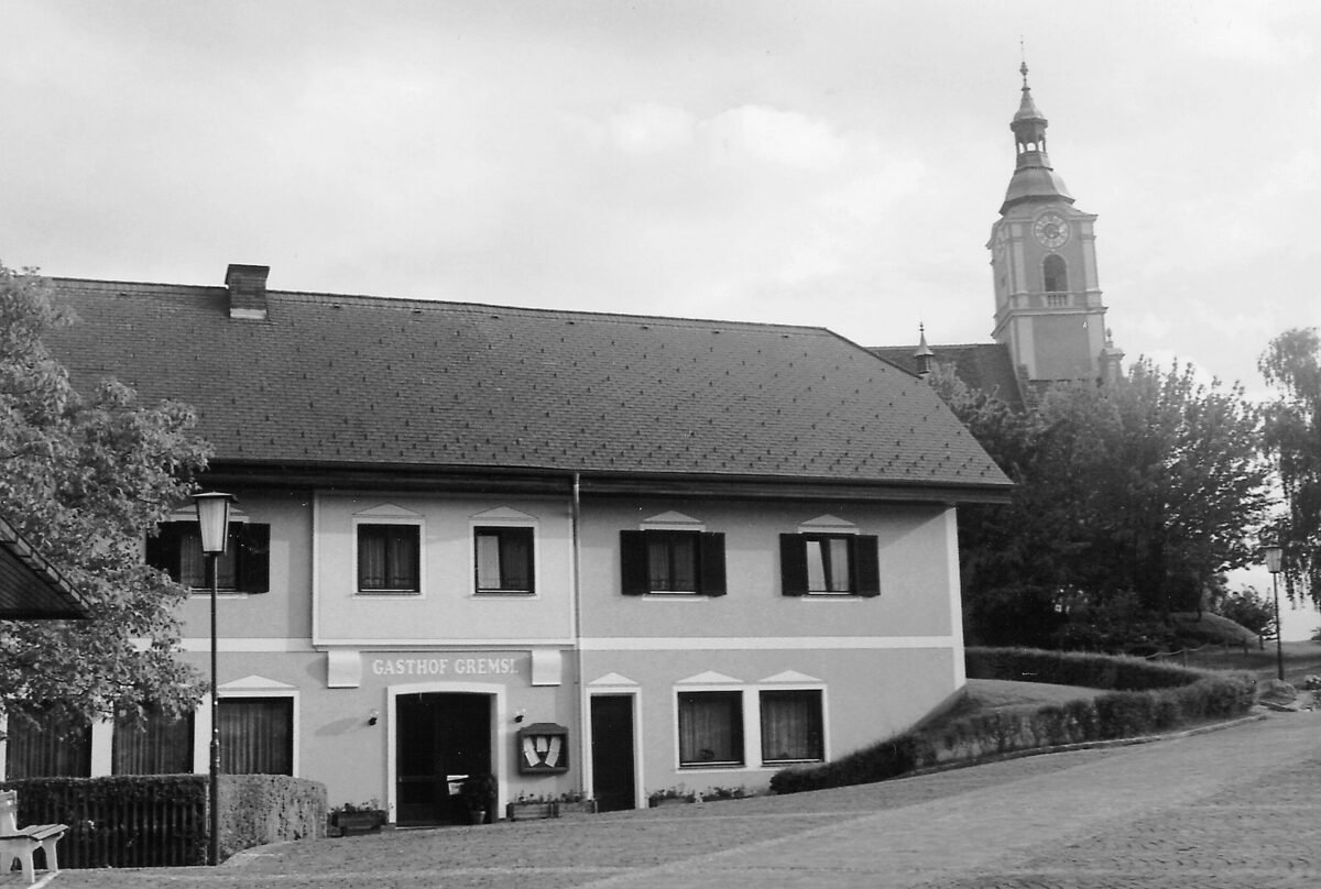 Historische Schwarzweiß-Aufnahme des Gasthof Gremsl am Pöllauberg, im Hintergrund der Turm der Wallfahrtskirche