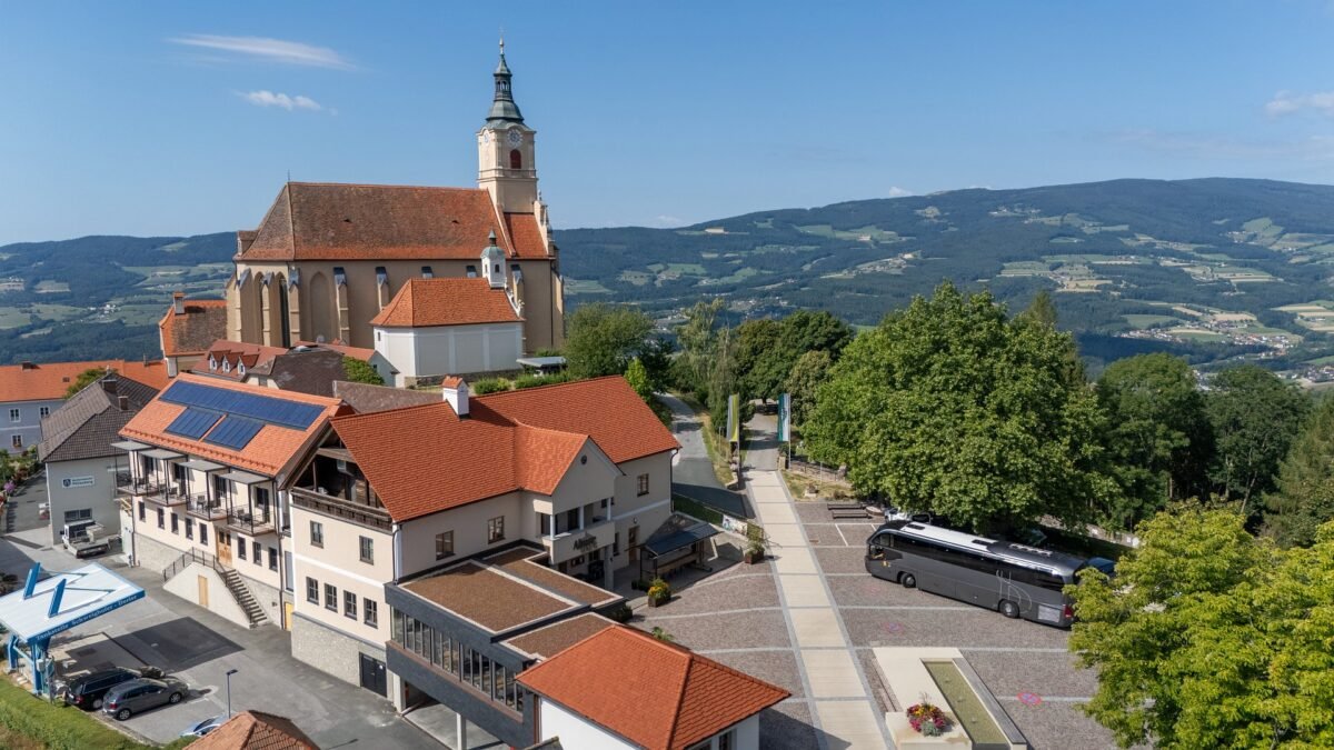 Luftaufnahme von Pöllauberg mit Reisebus am Parkplatz vor der Wallfahrtskirche