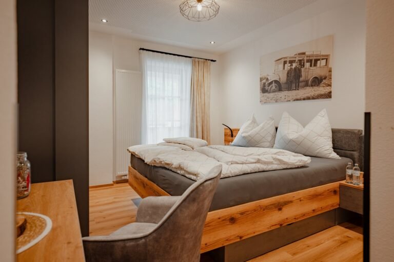 Doppelzimmer mit Altholzbett, Sessel und Fenster
