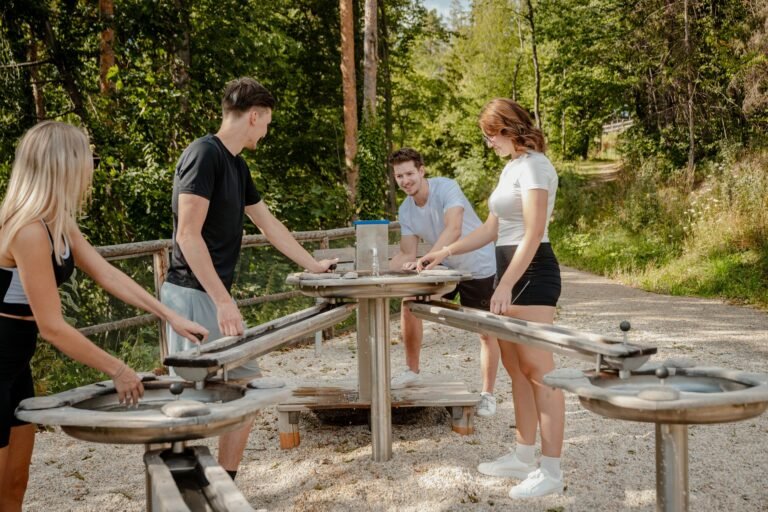 Vier Personen an einer Wasser-Erlebnisstation im Wald am Erlebnisweg
