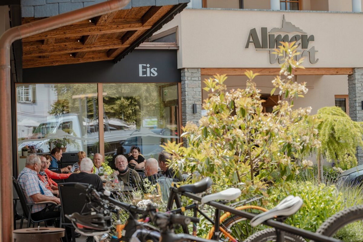 Gäste sitzen im Gastgarten des Almerwirt, davor abgestellte Fahrräder