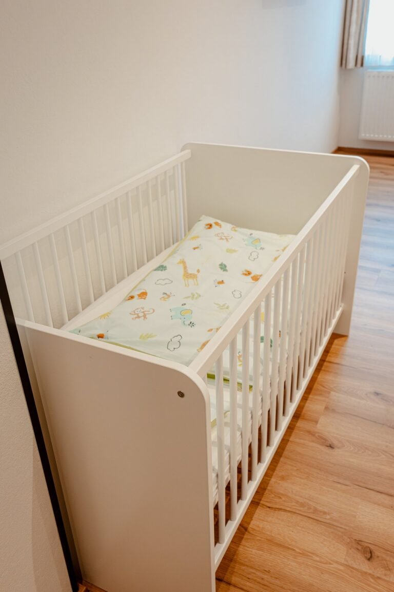 Weißes Kinderbett mit Bettwäsche im Zimmer