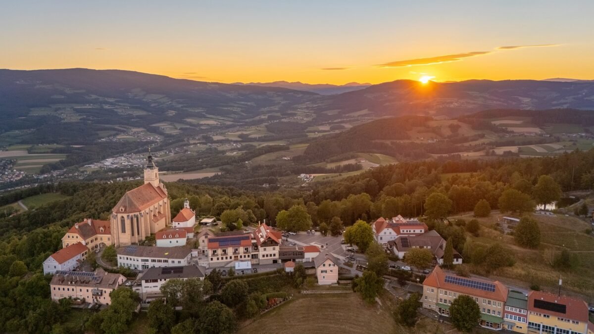 Luftbild von Pöllauberg mit der Wallfahrtskirche bei Sonnenuntergang über den Hügeln der Oststeiermark
