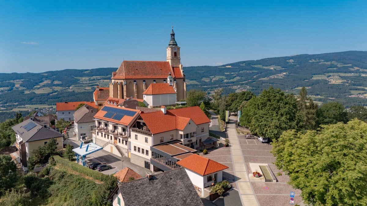 Luftbild der Wallfahrtskirche Pöllauberg mit dem Ort und den Hügeln der Oststeiermark