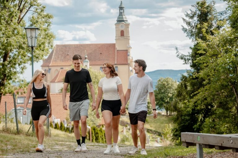 Vier Wandernde auf dem Weg am Pöllauberg, im Hintergrund die Wallfahrtskirche